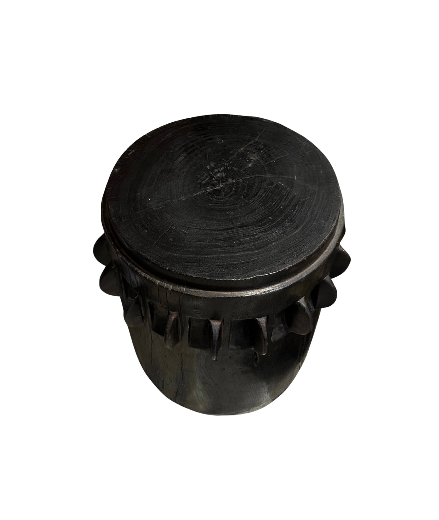 The Ebonized Wood Accent Table features a round, flat top and geometric carvings on its dark wooden sides, shown against a white background.