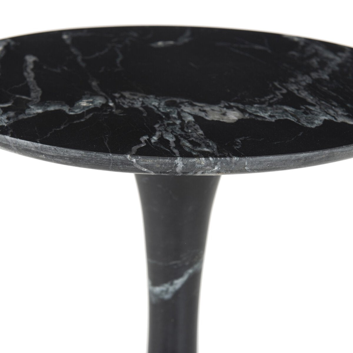 A close-up of the Sculpted Marble Side Table reveals its round black marble top with white veining, crafted from solid marble and supported by a matching black pedestal base.