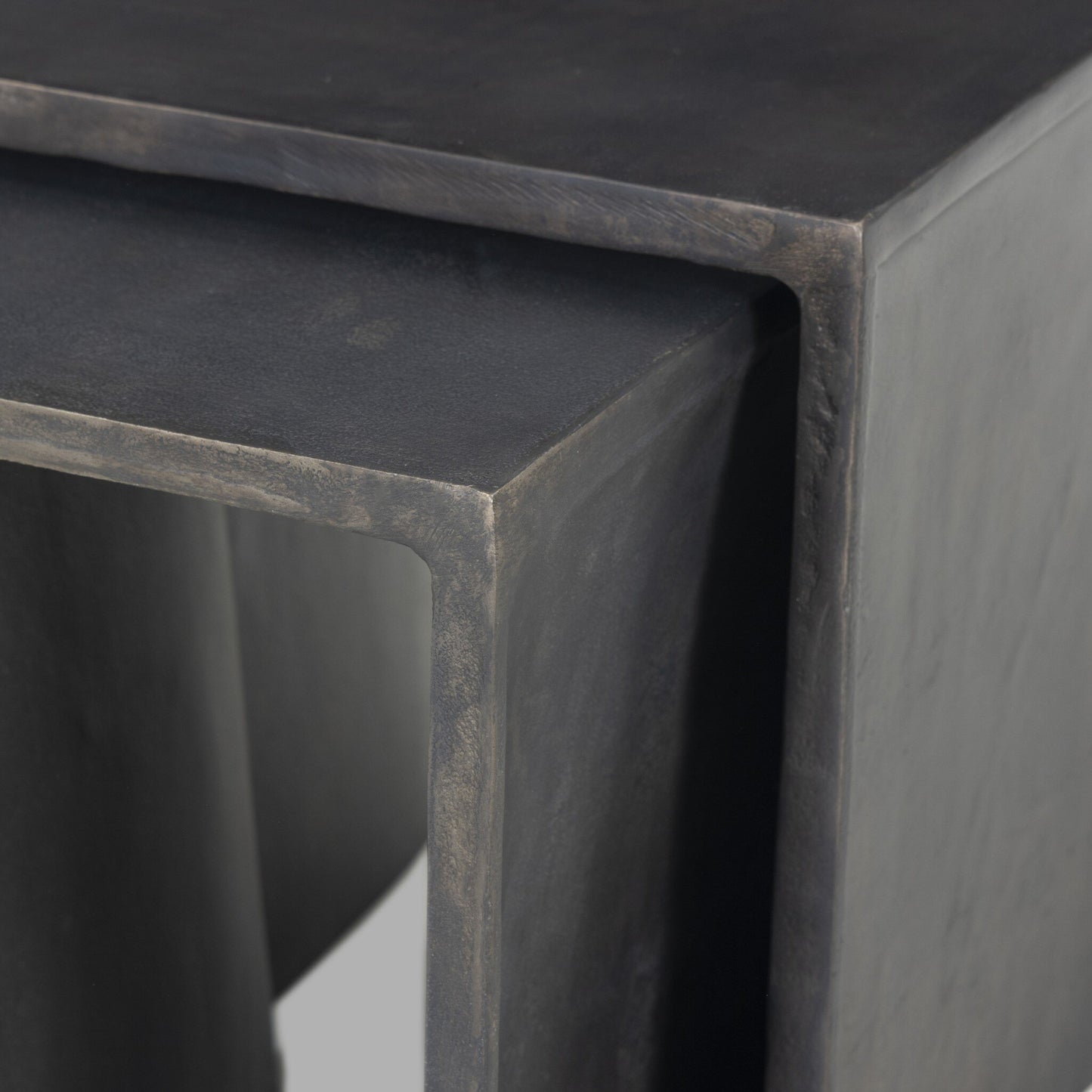Close-up of Aluminum Curved Legs | Outdoor Nesting End Tables featuring a modern, minimalist rectangular design with dark matte cast aluminum, smooth angular edges, and subtly curved legs.