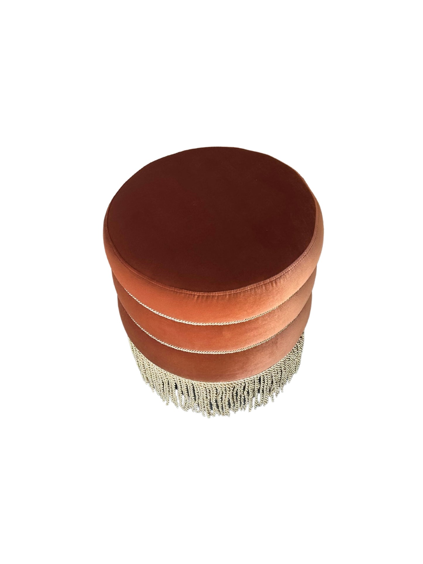The Fringed Velvet Small Ottoman in burnt orange velvet has a smooth top and decorative fringe trim around the base, displayed against a white background.