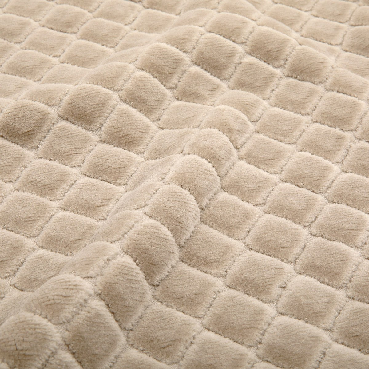 Close-up of the Velour Diamond Bath Mat, featuring a beige, quilted design made from 100% cotton with a textured, diamond pattern. The surface appears soft and plush, with raised, padded sections creating a cozy and inviting look.