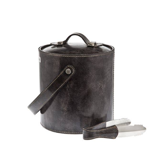 The Leather Ice Bucket W/tong Grey features Italian craftsmanship, a matching handle, white stitching, a lid, and metal ice tongs—making it a stylish addition to any home bar.