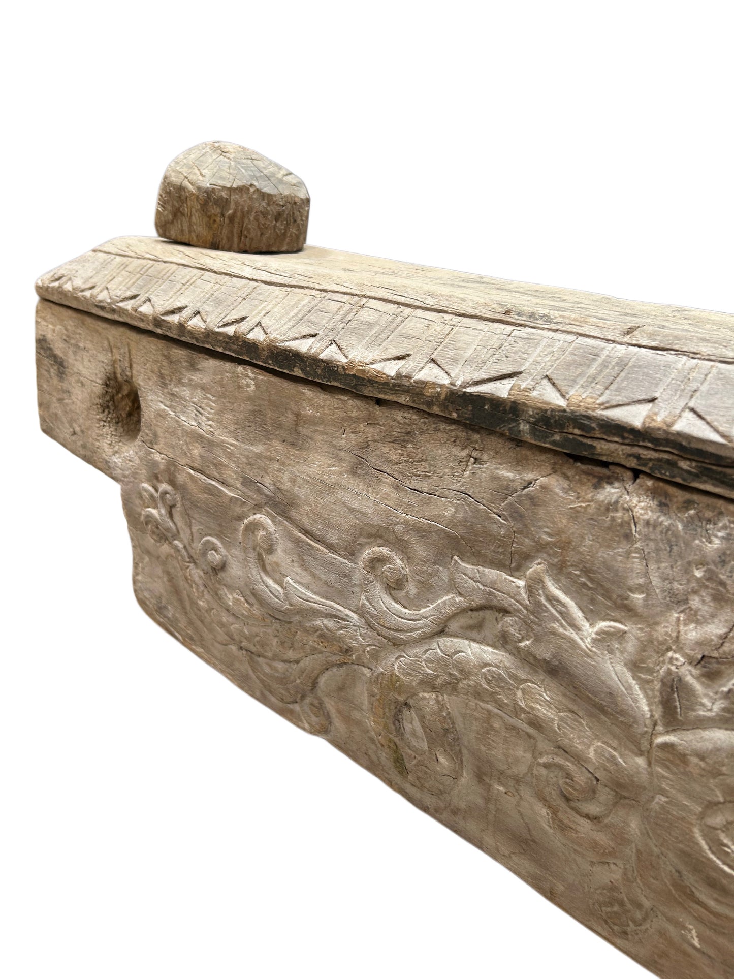 A close-up of a 19th-century Antique Wooden Dowry Chest highlights its intricate floral and geometric carvings, rounded top knob, and textured, weathered wood surface.