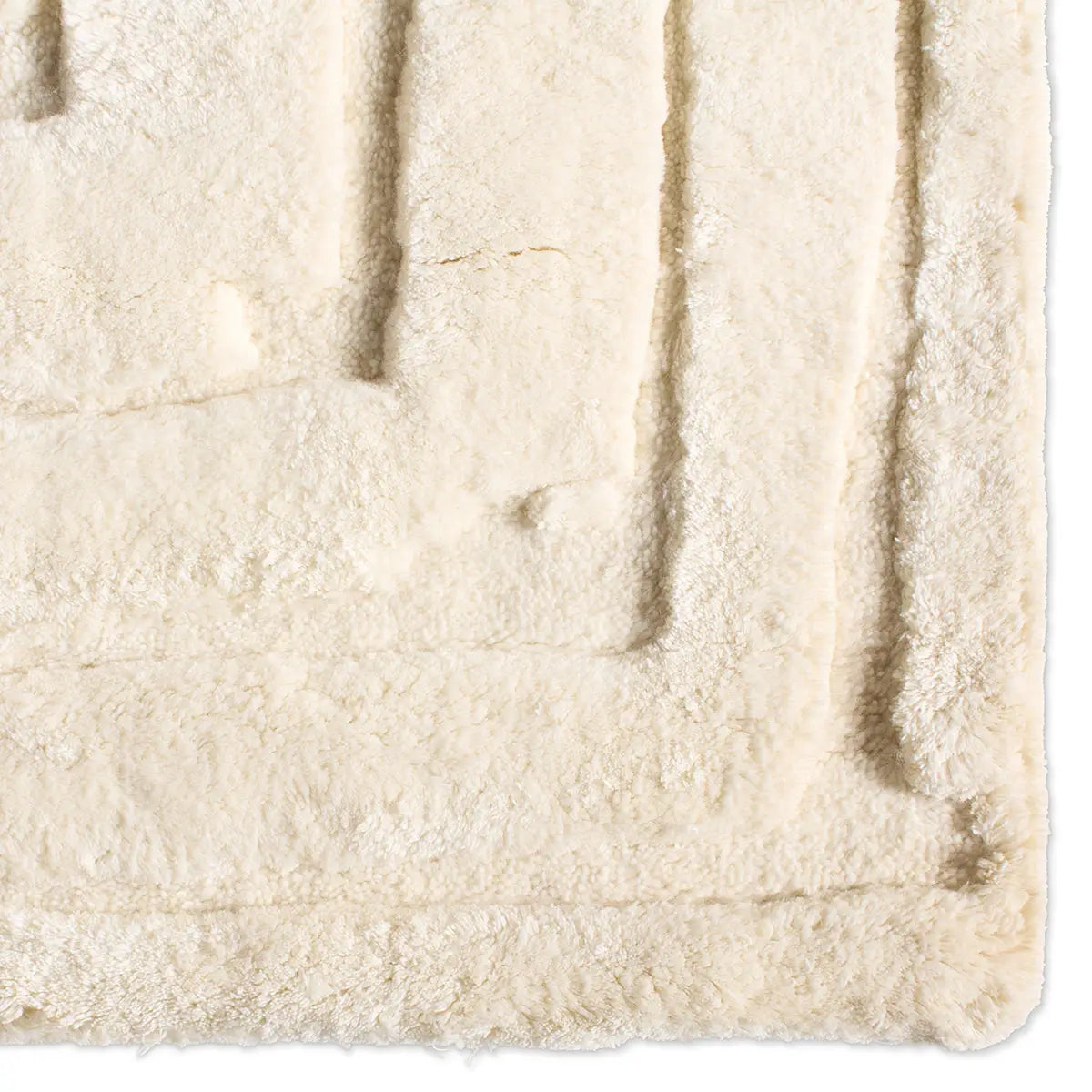 A close-up of the Centric Linear Wool Rug 10 x 14 highlights its soft, plush texture, cream color, and raised border design that forms a subtle rectangular pattern—evoking the coziness and quality of fine New Zealand wool.