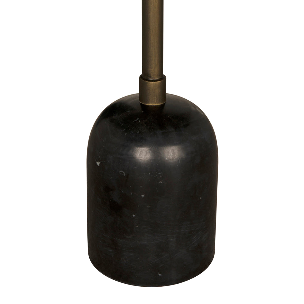 A close-up of the Shantu Side Table with Stone Top shows its black, cylindrical, dome-shaped base with a marbled matte finish, featuring an aged brass rod extending from the top center.