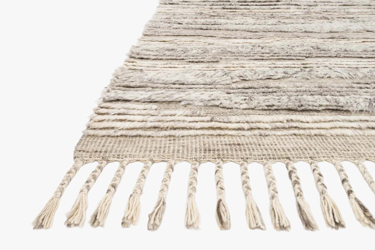 A close-up of the Indian Wool Rug With Fringes in beige and cream, featuring thick twisted tassels along the edge, shown against a white background. Size: 8'6x11'6.