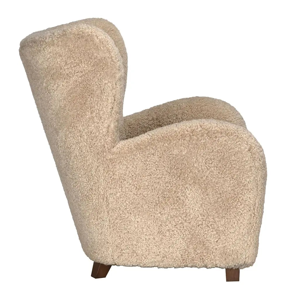 Side view of the Teddy Fleece Arm Chair: a plush, beige upholstered recliner with a high back and armrests in soft curly faux-shearling, supported by short wooden legs—an inviting, cozy addition to any living room furniture set.