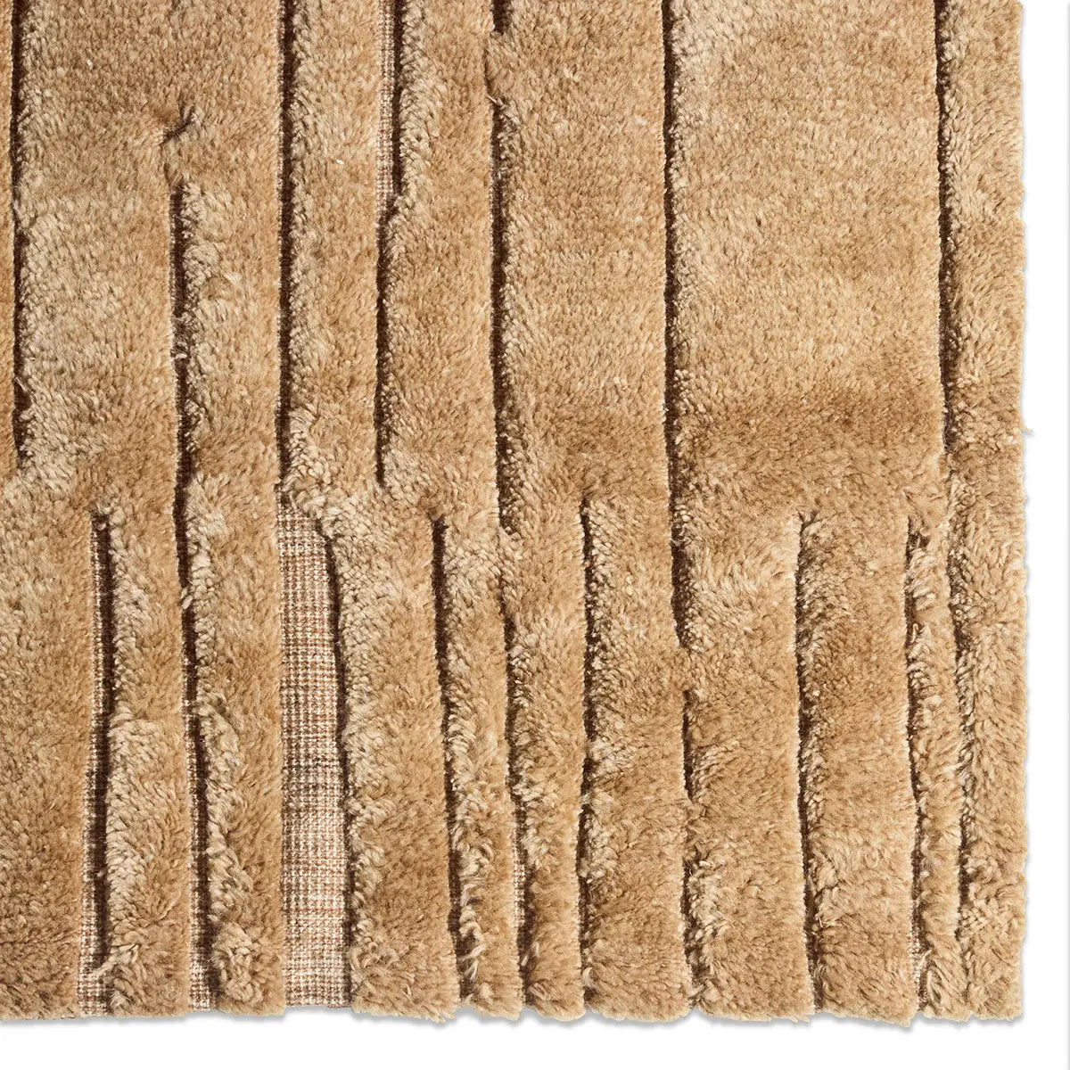 Close-up of the Abstract Geometric Rug, featuring tan, textured shaggy fibers crafted from premium New Zealand wool, with rectangular cut sections that reveal a subtle grid pattern beneath the plush surface.