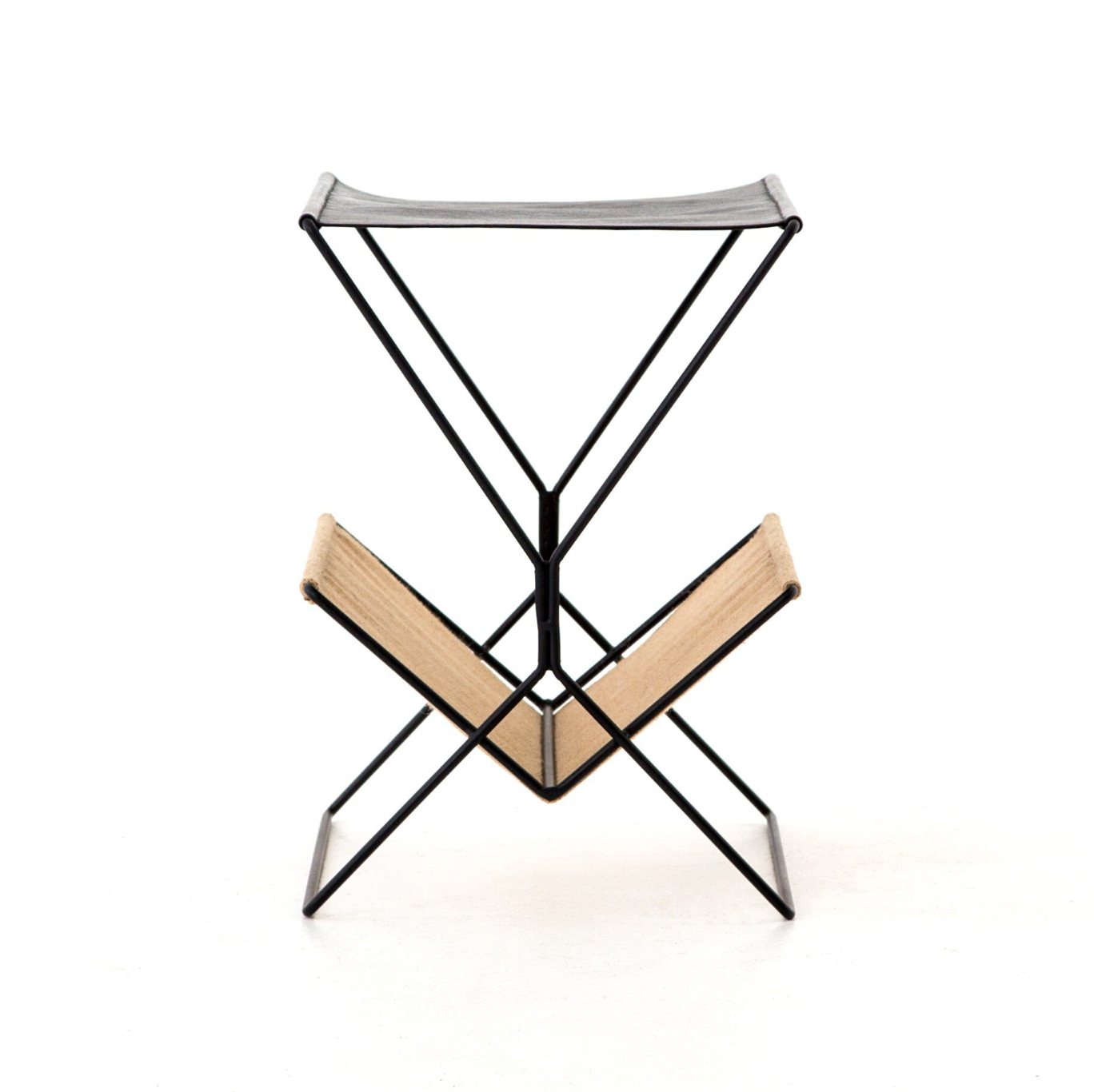 The Leather & Hemp Magazine Rack is a minimalist black metal stand with a beige hemp V-shaped sling at the bottom and a flat gray leather sling on top, displayed against a white background.