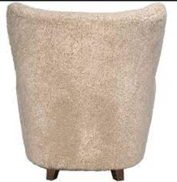 The Pola Chair is shown from behind in beige teddy fleece, featuring a high back and wooden legs that add cozy comfort—ideal as a contemporary occasional chair.