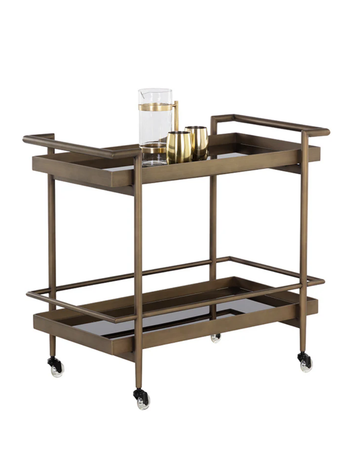 The Smoke Glass Bar Cart features two black glass tiers, four wheels, and an antique brass frame. The top shelf displays three gold drinkware pieces and a clear glass pitcher filled with water.