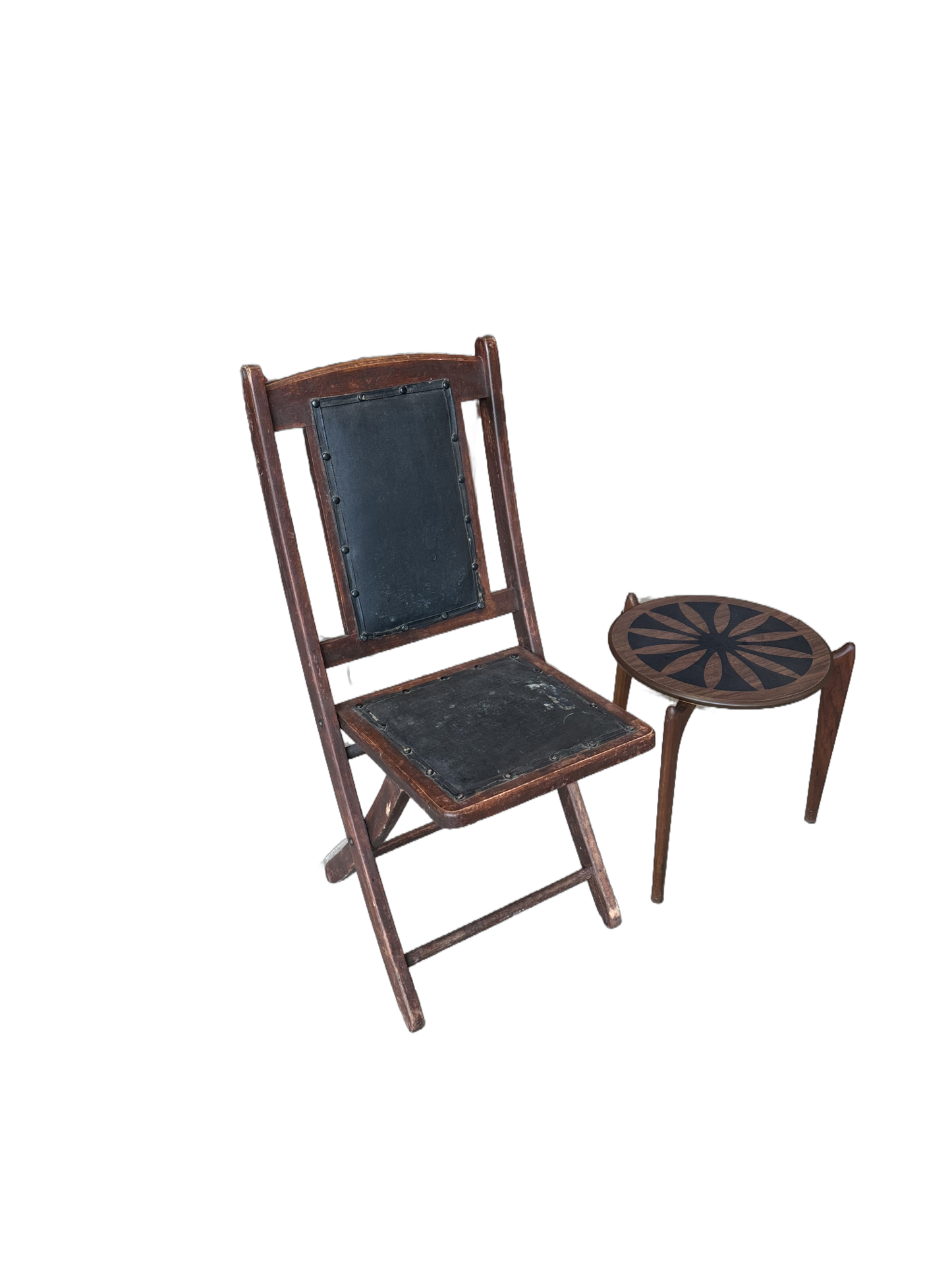 A Vintage Leather Folding Chair sits beside a small round wooden side table with a decorative sunburst pattern on the top.