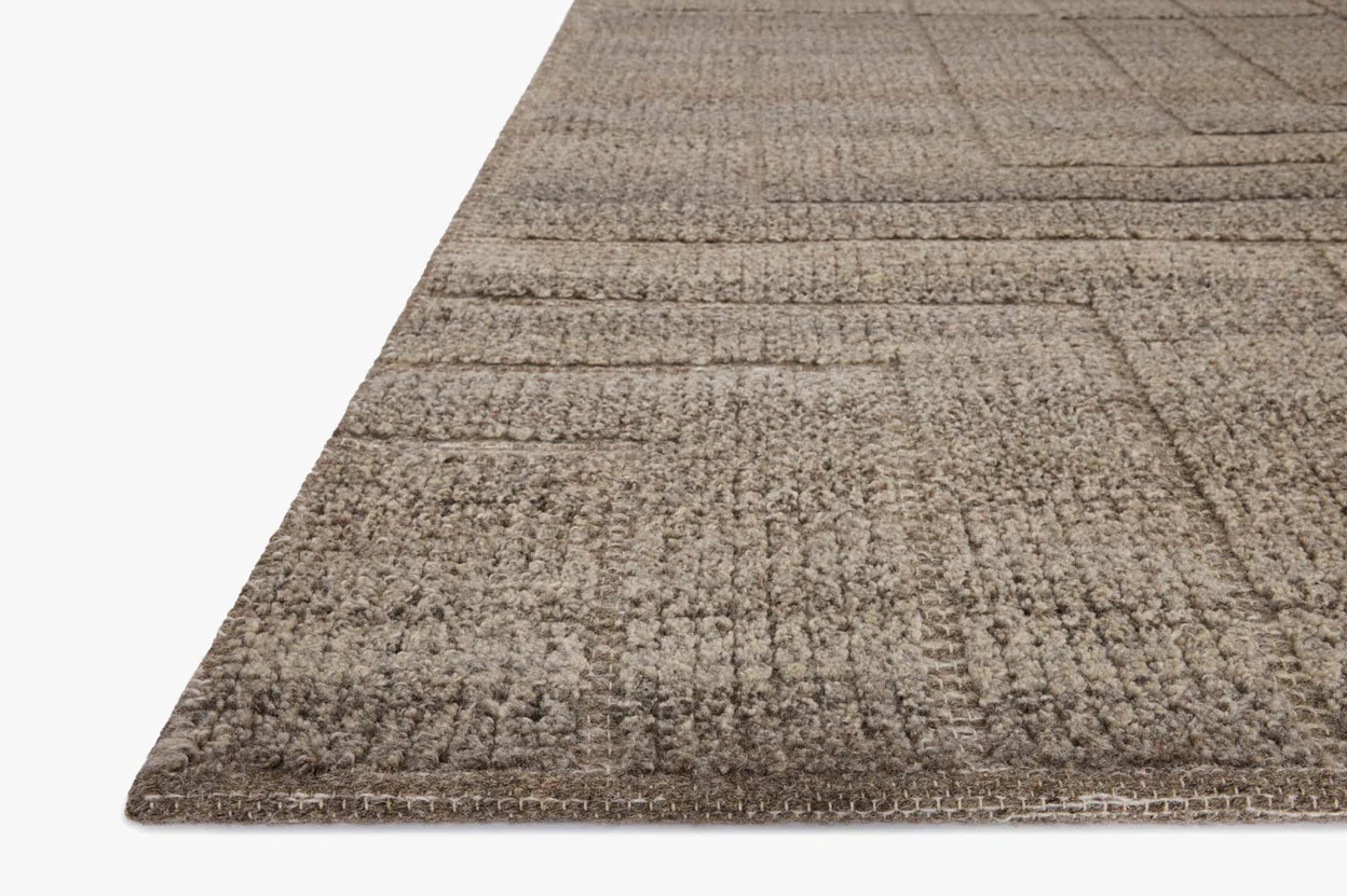 Close-up of the Modern Hand Loomed Brown Fade Rug (8'6x11'6) shows its textured beige surface with a geometric pattern and raised details, against a white background. Fibers are visible. Available in multiple sizes to fit your space.