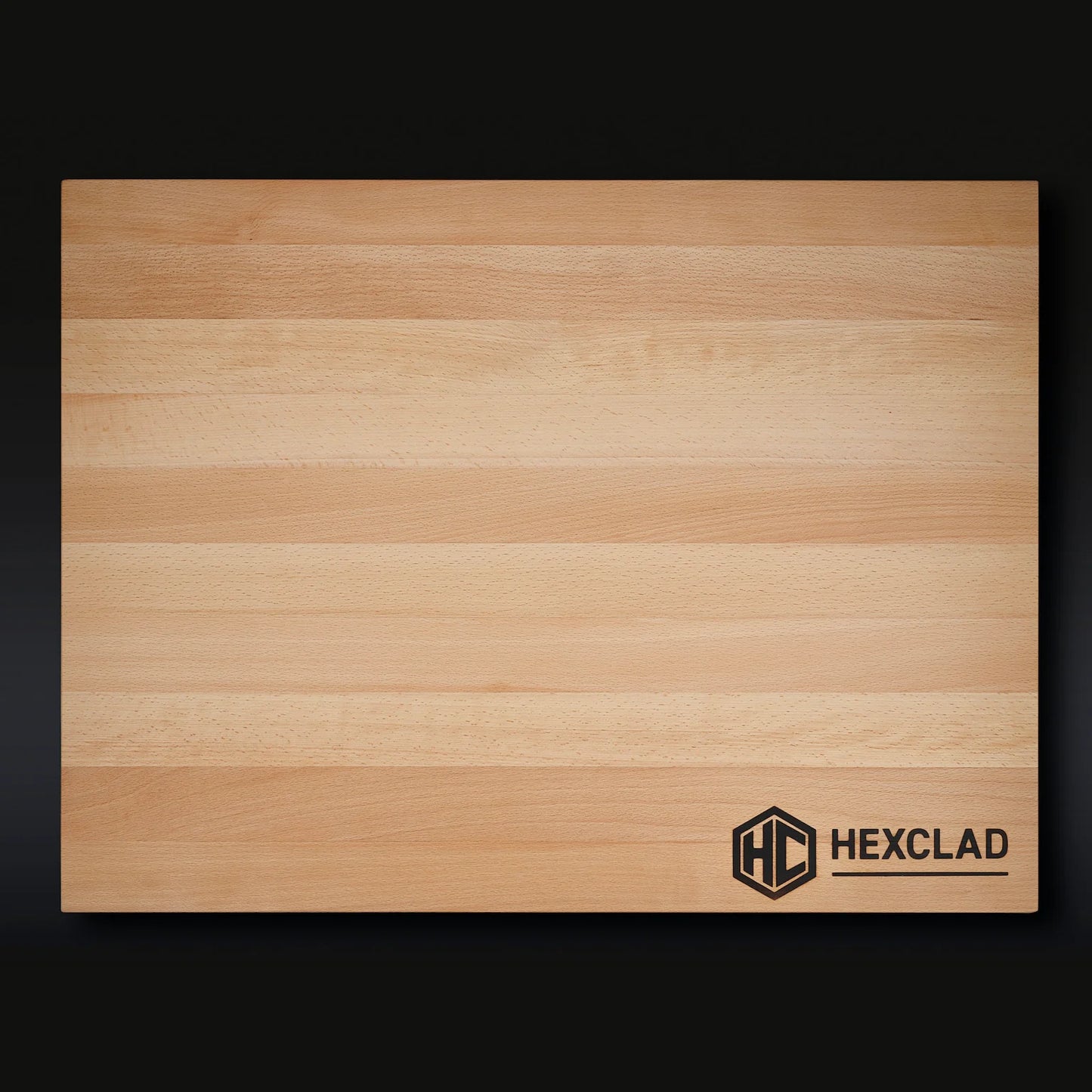 The HexClad XL Cutting Board is a rectangular beechwood board with light and medium stripes and a black HexClad logo on the bottom right, shown against a dark background.