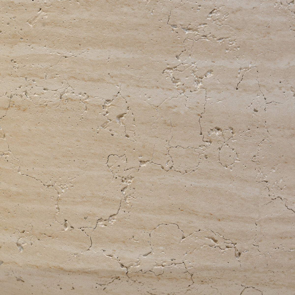 Close-up of the Concrete End Table in Sand highlights its beige, rough-textured surface with visible cracks, crevices, and color variations, creating a weathered look resembling natural stone with a modern sand finish.