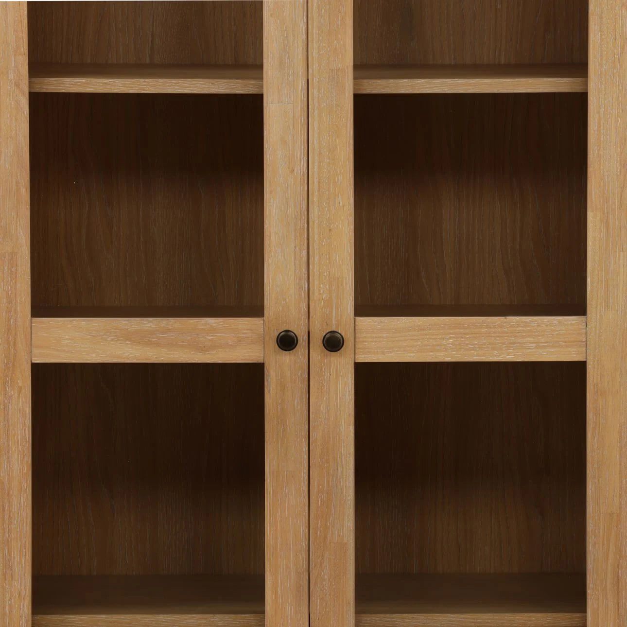 A close-up of the Natural Oak Veneer Cabinet shows glass doors with two round black handles and three empty shelves inside. The wood features a light, natural oak finish.