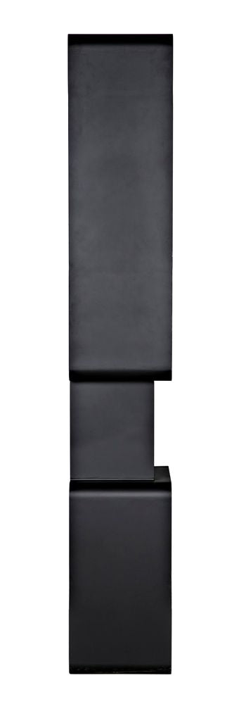 The Larra Bookcase is a tall, minimalist black piece featuring three stacked rectangular shelves, with the middle shelf slightly shifted right. Subtle welding marks highlight its handmade metal construction and geometric stepped design.