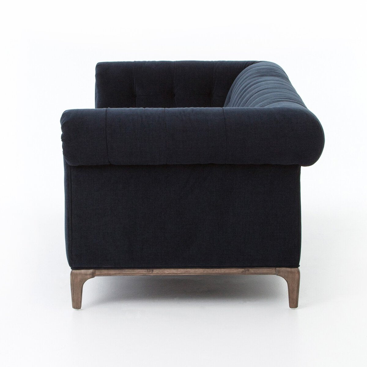 Side view of the Chesterfield Navy Sofa with dark navy blue upholstery, tufted back and arms, and short light wooden legs against a white background—ideal for stylish comfort with perfect overall dimensions.