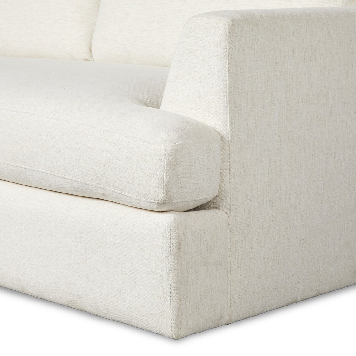 Close-up of the corner and armrest of the Classic Frame 2pc Sectional, a modern cream-colored sofa with soft textured upholstery, thick seat cushion, and minimalist design. Available with left or right chaise options.
