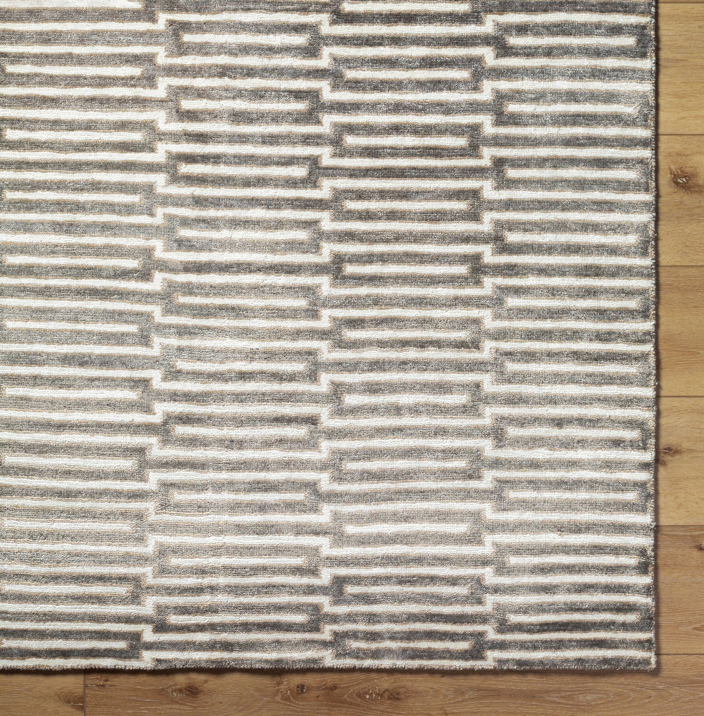 The Viscose Pattern Rug (8'x11') features a repeating geometric pattern of gray and white rectangles. Shown partially on a light wooden floor, it adds modern style to any space.
