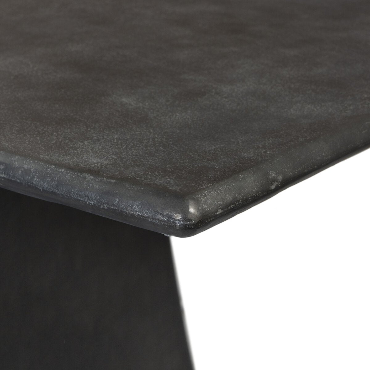 Close-up of the corner of the Tapered Pedestal Base Outdoor Table, featuring an aged grey aluminum finish with a textured surface and slightly rounded edges, set against a white background.