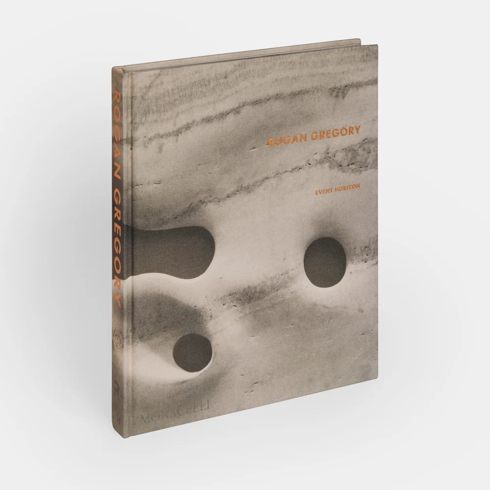 A hardcover book titled “Event Horizon Rogan Gregory” features a textured, marble-like gray cover with abstract, sculpted forms and engraved orange text.