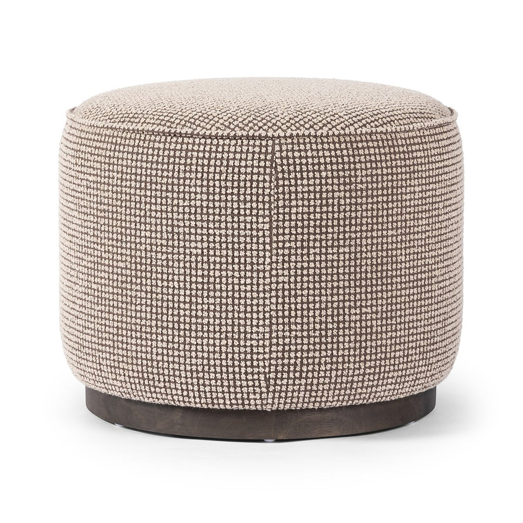 The Round Ottoman features textured beige fabric upholstery and a dark, solid base, displayed against a white background.