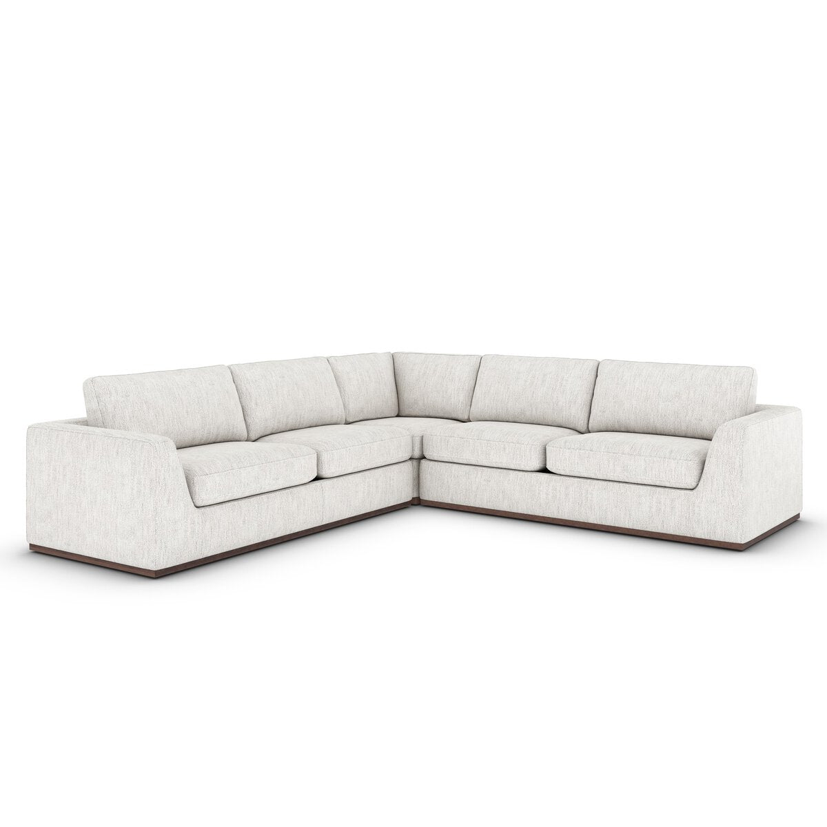 The Simple Modular Corner Sectional is a modern L-shaped sofa with light beige upholstery, wide armrests, a low-profile wooden base, and heirloom Italian leather sourced from renowned tanneries.