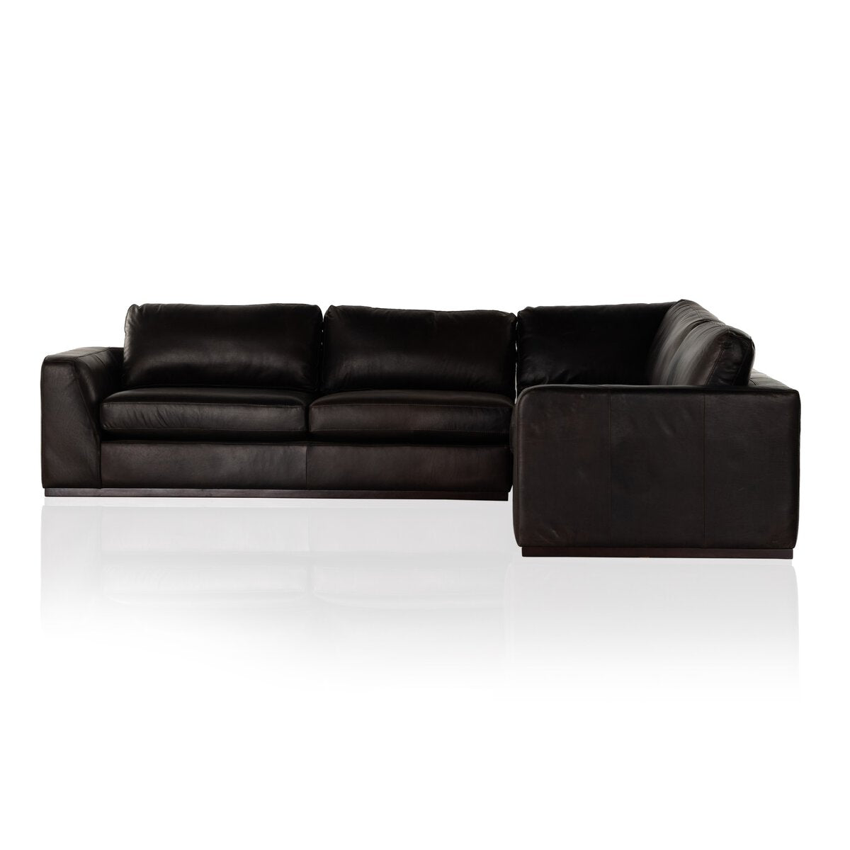 The Simple Modular Corner Sectional features wide armrests and plush cushions, crafted from black heirloom leather and showcased against a white background.