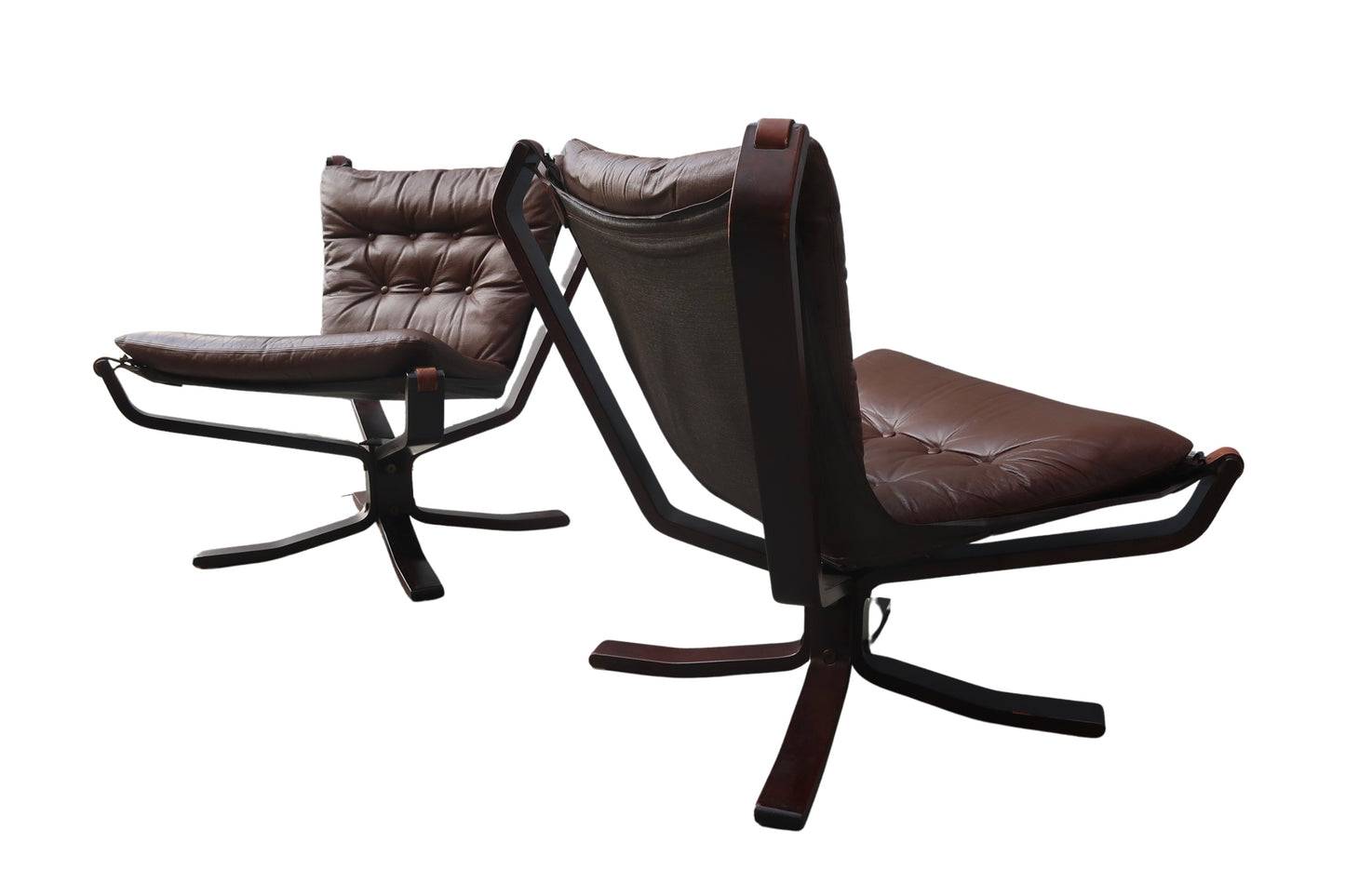 A pair of Vintage Falcon Chairs with brown leather tufted cushions and dark wood swivel bases are shown against a white background.