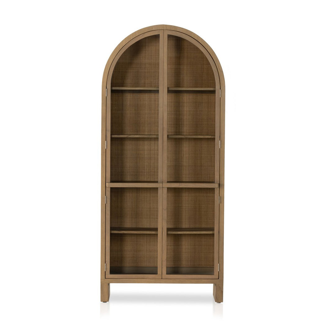 The Woven Arched Cabinet is a tall, freestanding wooden storage piece with an arched top, glass-paneled double doors, multiple interior shelves, and a natural light brown finish.