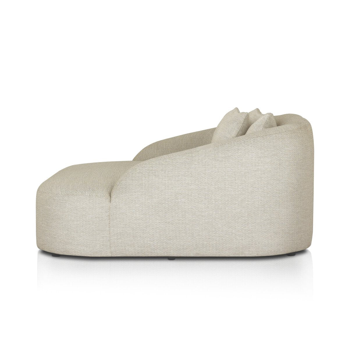 Side view of the Outdoor Day Bed—a modern, armless lounge chair in sand upholstery with a curved back and two matching cushions, styled like an upholstered outdoor day bed, isolated on a white background.
