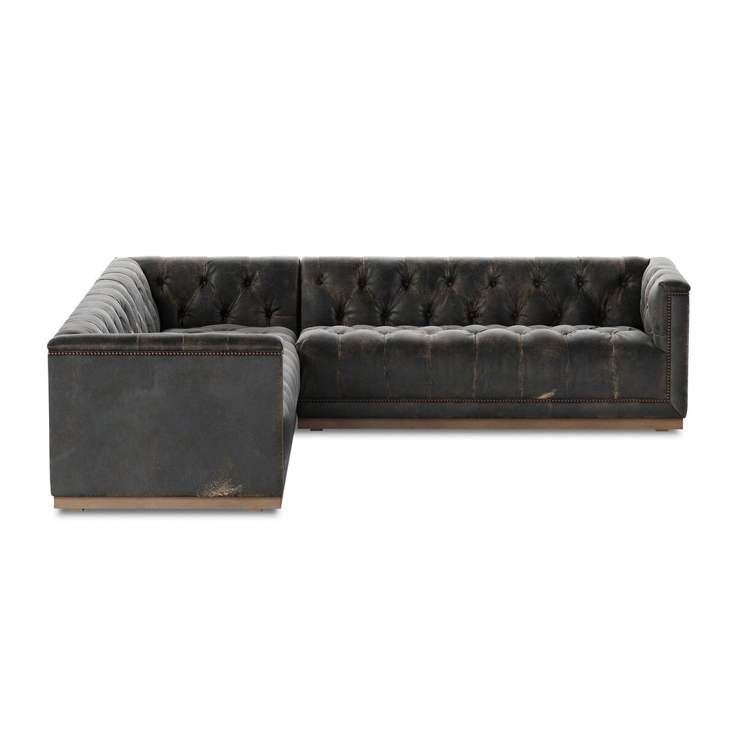 The Maxx 3-Piece Sectional is a dark gray, tufted leather L-shaped sofa with a low back and studded trim. Featuring distressed leather for a vintage look, this standout piece rests on short wooden feet.