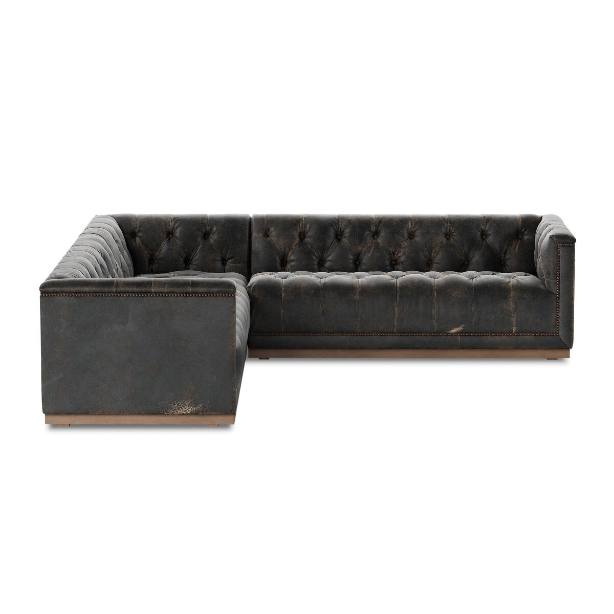 The Maxx 3-Piece Sectional is a dark gray, tufted leather L-shaped sofa with a low back and studded trim. Featuring distressed leather for a vintage look, this standout piece rests on short wooden feet.