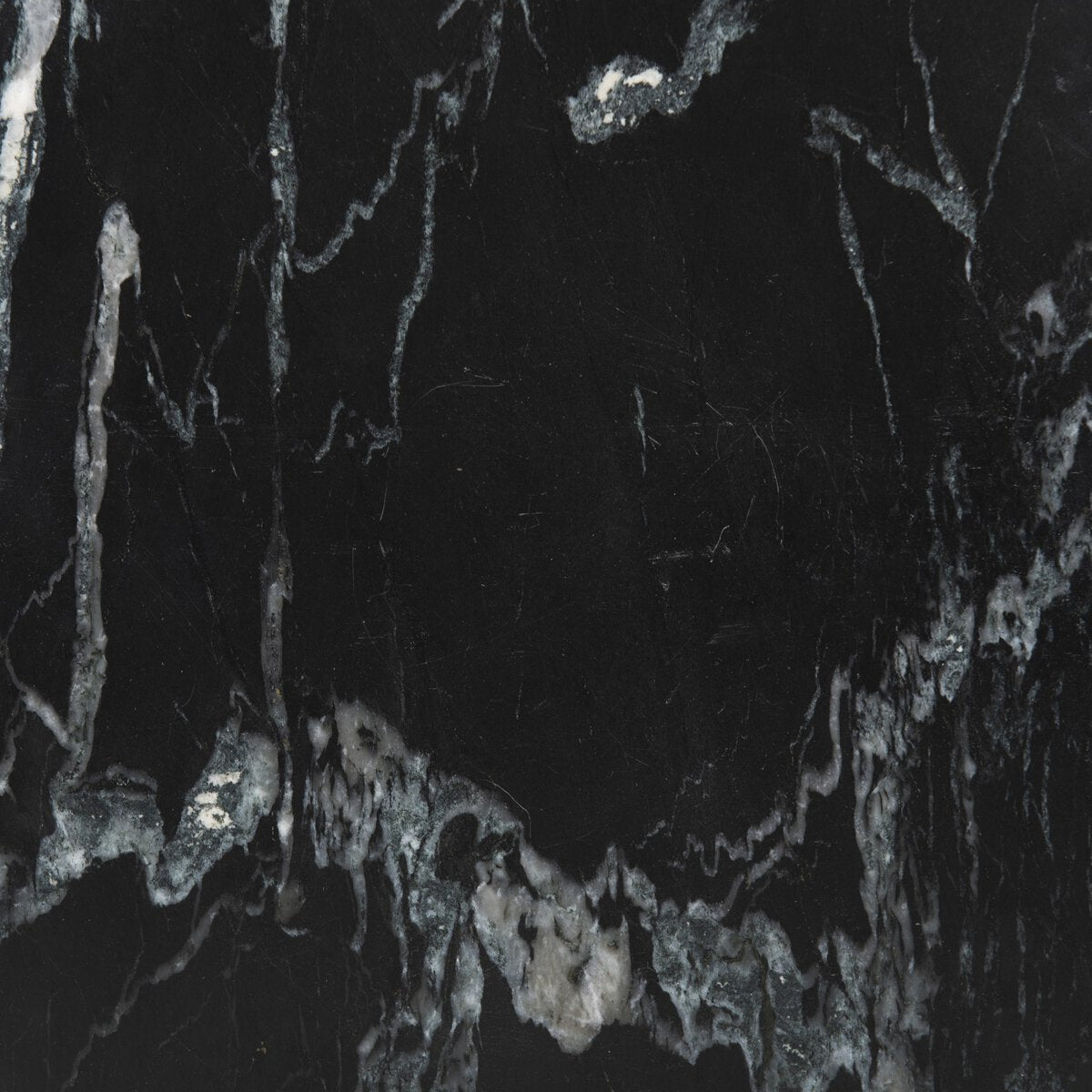 Close-up of the Sculpted Marble Side Table showcases its black marble surface, featuring irregular white and gray veining patterns that create a unique, natural abstract texture.