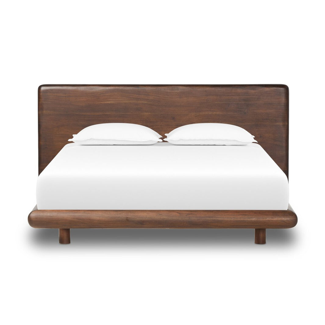 The Brown Acacia Bedframe features a large rectangular headboard and dark brown finish, available in queen or king size. Shown with white bedding and two pillows against a plain white background.