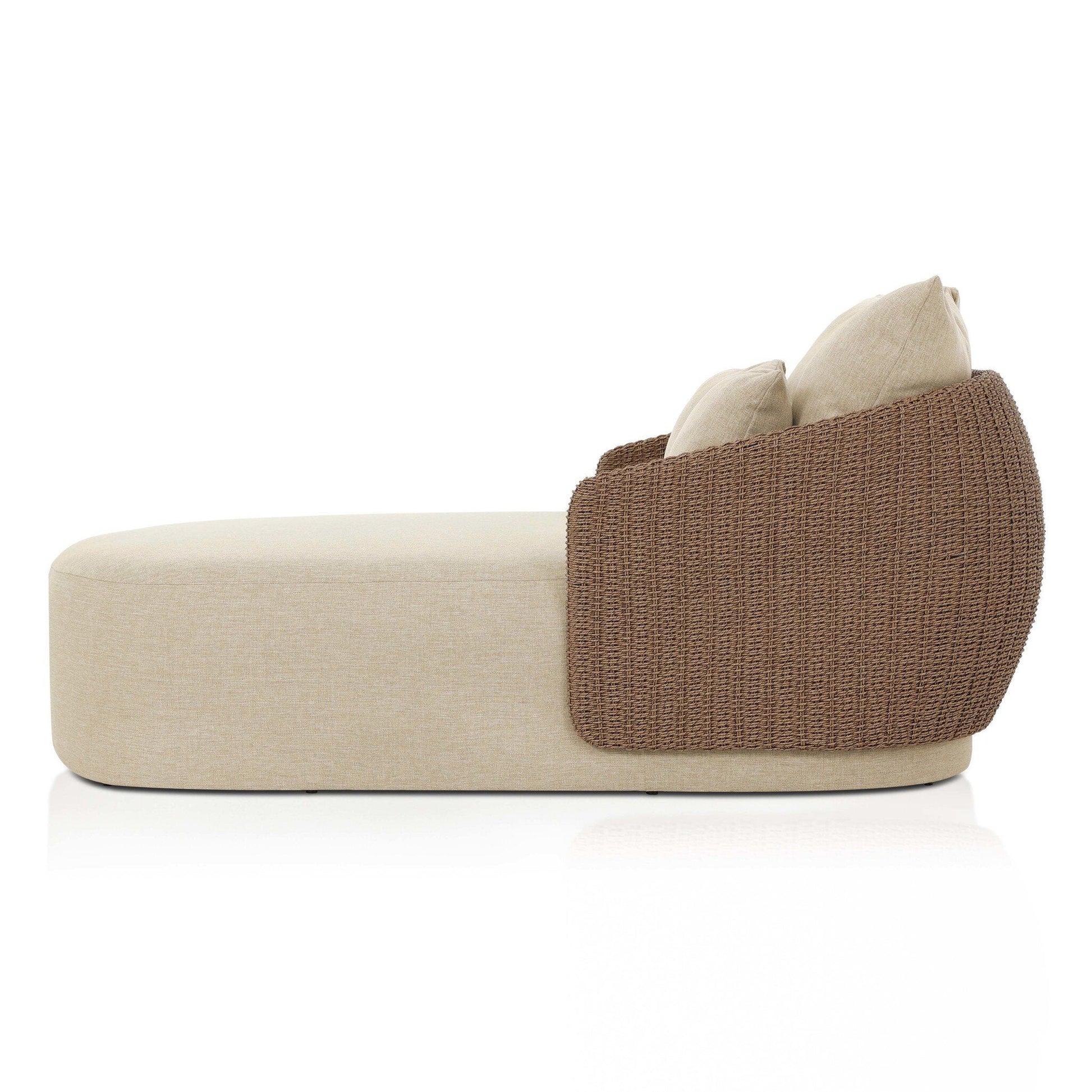 The Maven Outdoor Double Chaise is a modern beige lounge with two matching cushions and a rounded brown wicker backrest, shown in profile against a white background—easy to fit with standard furniture sizes and ideal for versatile outdoor spaces.