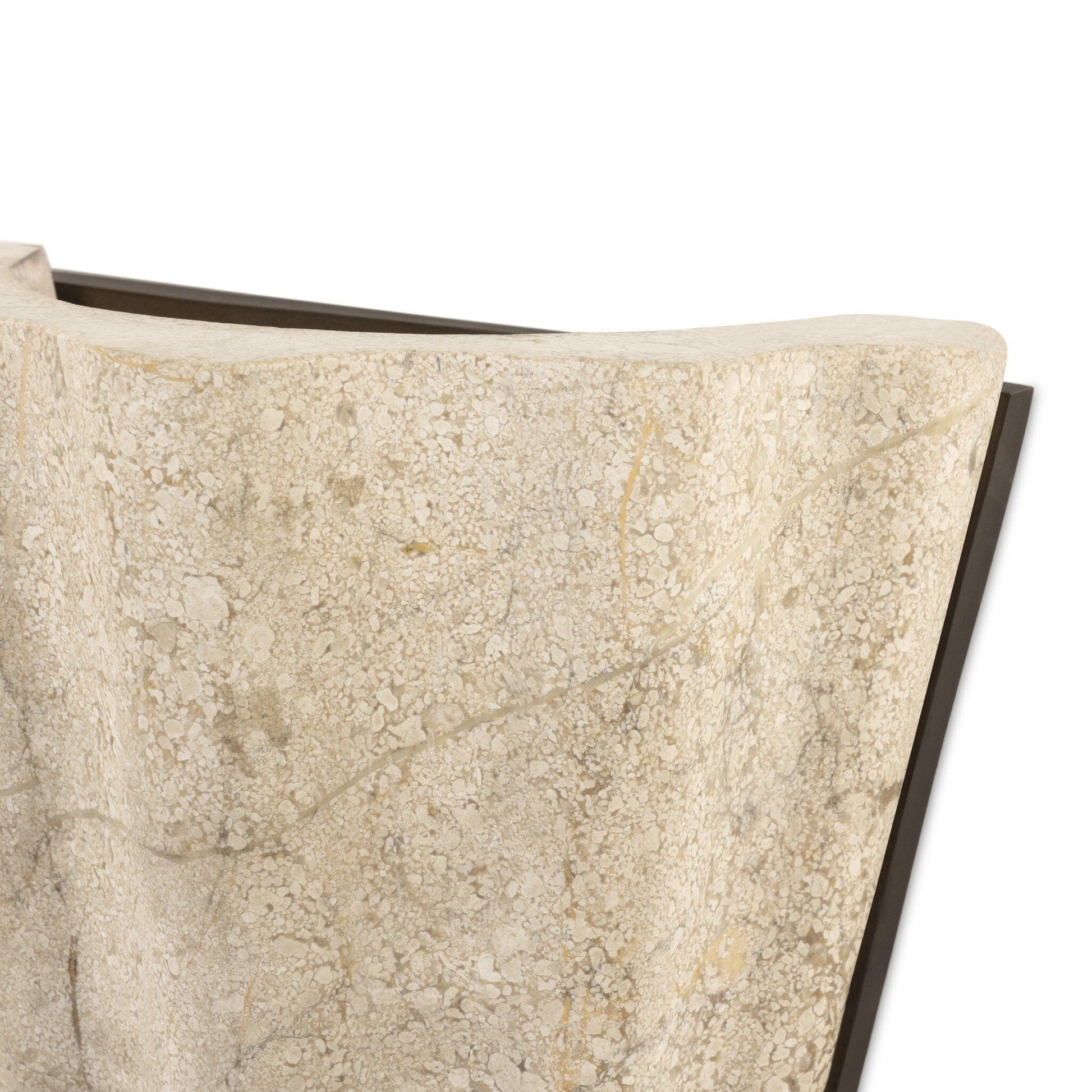 Close-up of the Astra Sconce’s textured beige, stone-like surface with a wavy edge and natural patterns, set against a white background. Measures 8.50w x 4.50d x 7.75h, with a dark angular detail partially visible behind it.