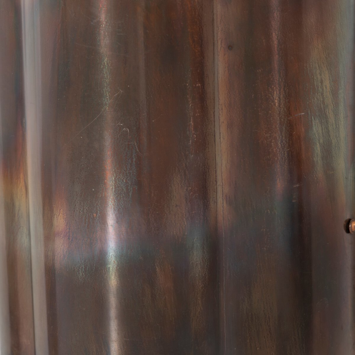 A close-up of the Rialto Sconce reveals a slightly reflective, acid-wash copper finish with subtle iridescent hues, vertical lines, and minor scratches.