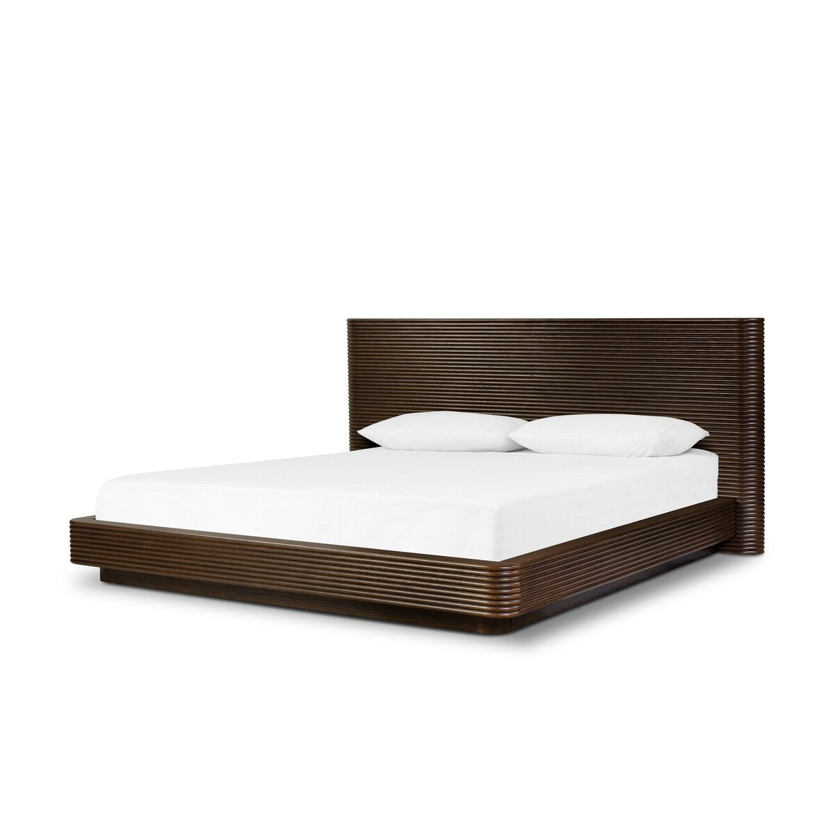 The Benny Bed is a modern dark wood platform bed with horizontal grooves, a tall matching headboard, and two white pillows on a white mattress—perfect for anyone mindful of furniture measurements in their space.