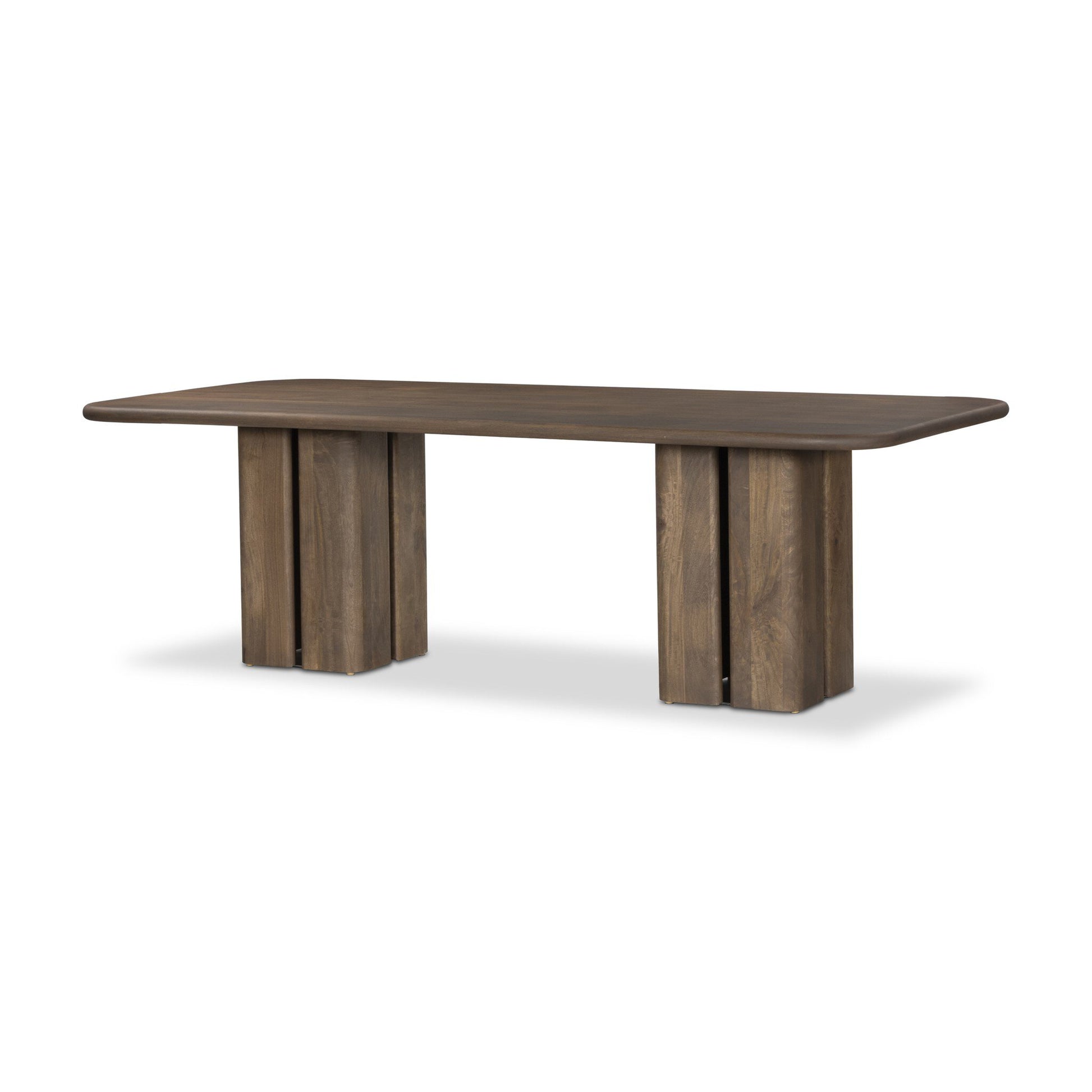 The Rishi Dining Table is a large rectangular wooden table with rounded corners and two wide block pedestal legs. Its smooth dark brown finish and minimalist design make it perfect as office furniture or a conference table.