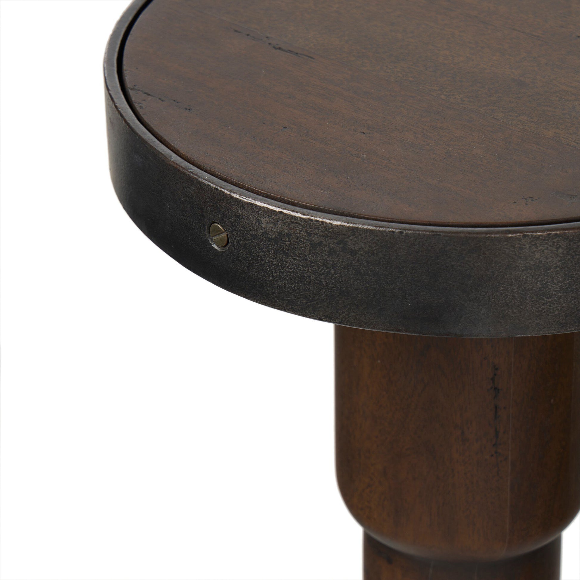 A close-up view of the Mizu End Table’s round wooden tabletop with a dark metal rim and a visible screw, plus part of its thick, cylindrical wooden leg. Overall Dimensions: 10.00"w x 10.00"d x 24.75"h.