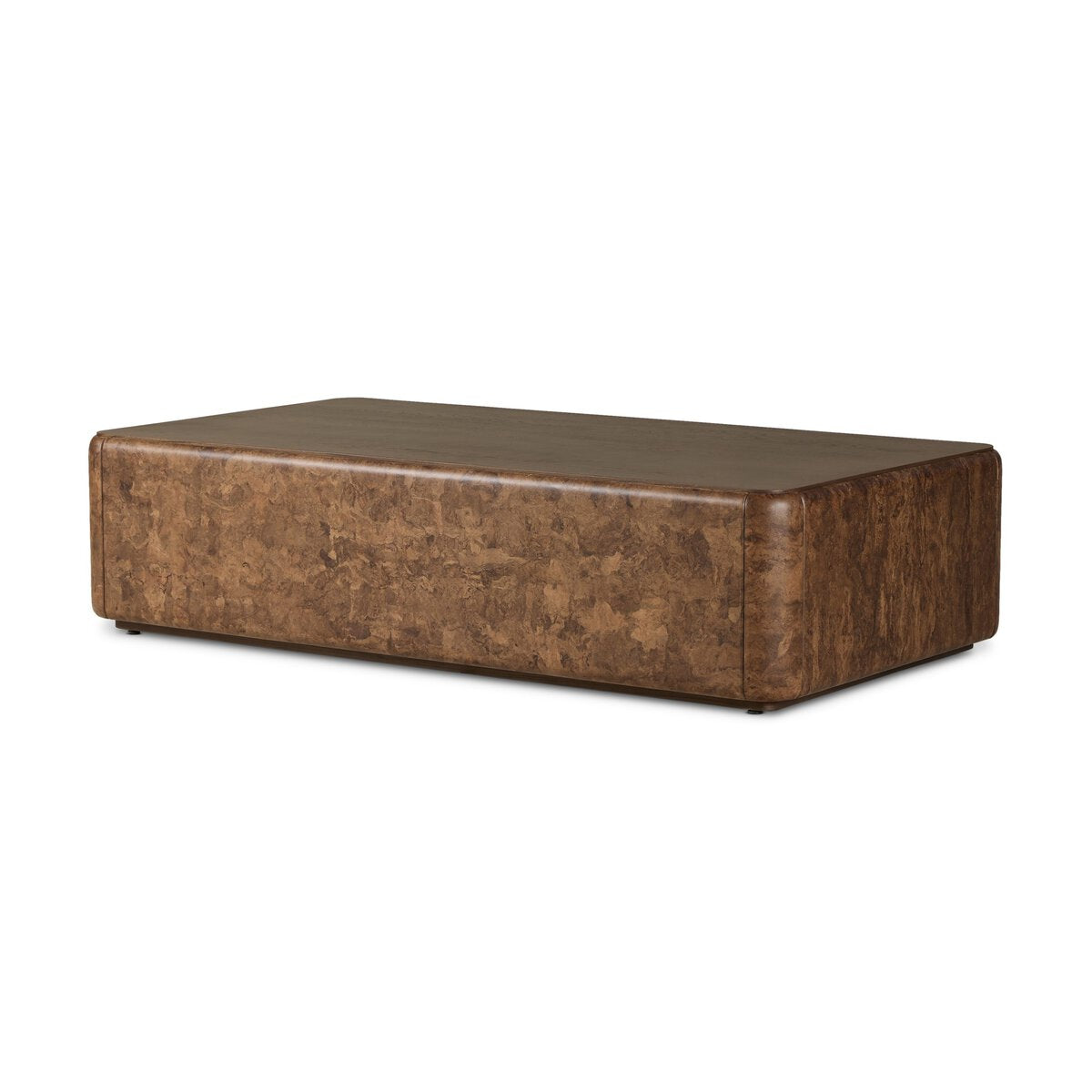 The Lola Coffee Table is a rectangular brown table with a textured surface and rounded edges, featuring a minimalist modern design that complements various sofa sizes.