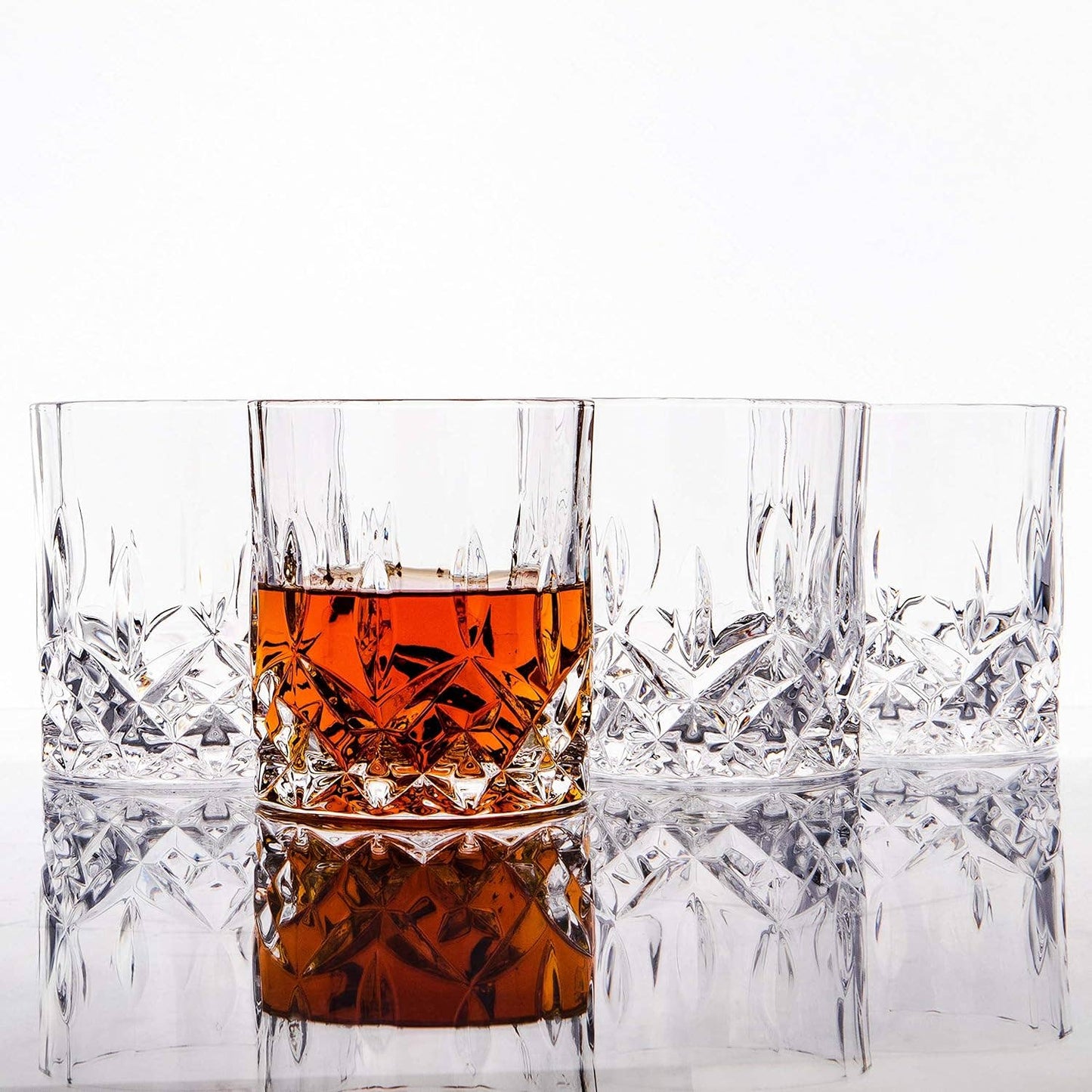 The Crystal Cut Old Fashioned Whiskey Glass 10oz (1pc) is elegantly displayed on a reflective surface with amber whiskey. This dishwasher-safe glass makes a perfect gift for whiskey lovers and adds sophistication to any setting.