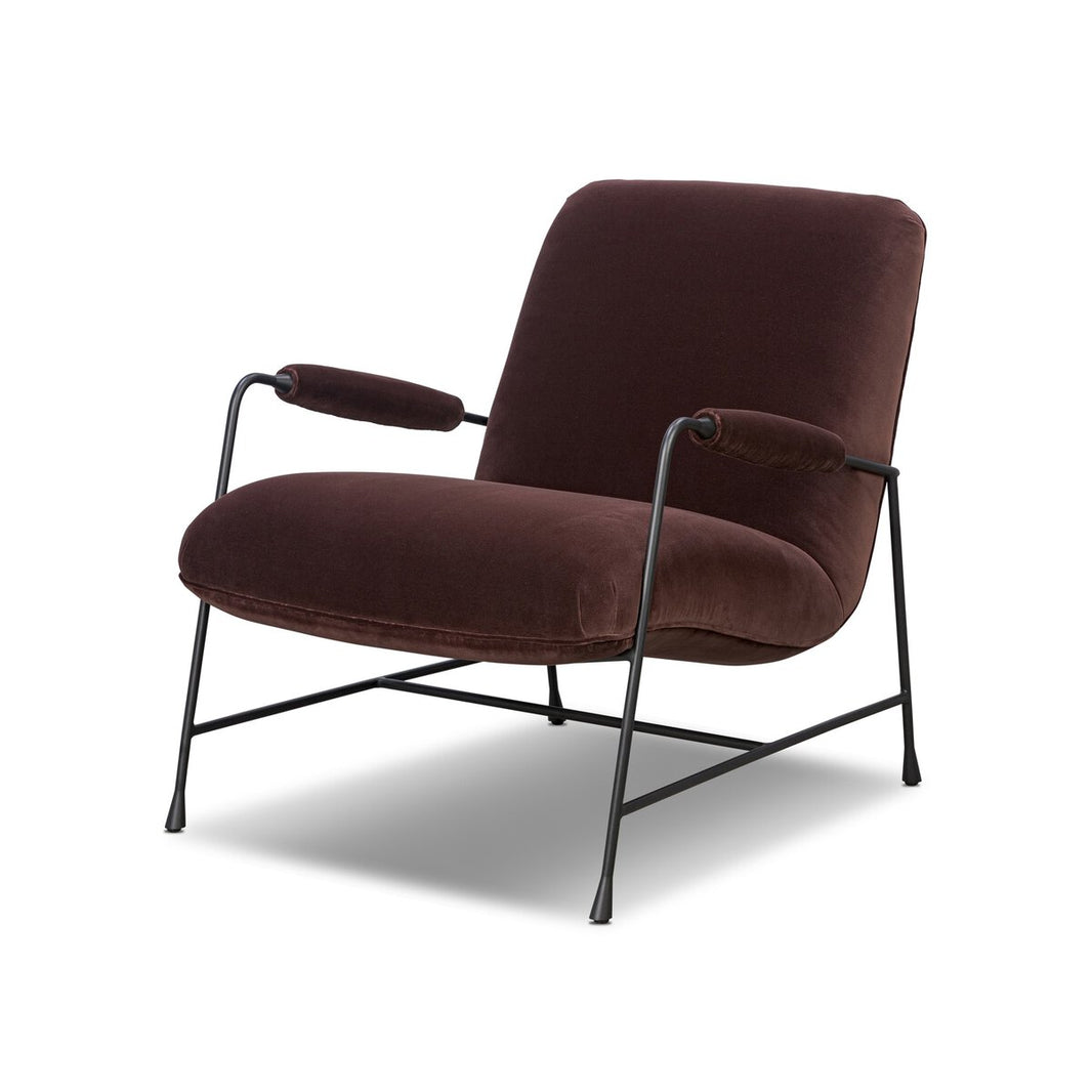 The Steel Upholstered Armchair features a plush dark brown velvet seat and backrest, thin black metal frame, and padded armrests, all set against a white background.