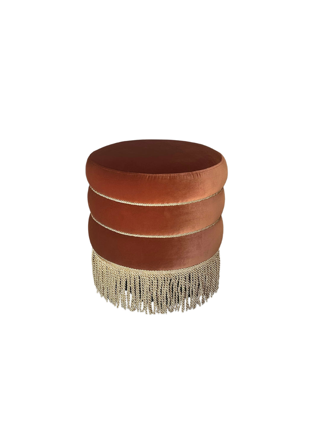The Fringed Velvet Small Ottoman features brown velvet upholstery, three stacked cushion layers, and gold fringe trim at the base, creating a stylish statement against a white background.