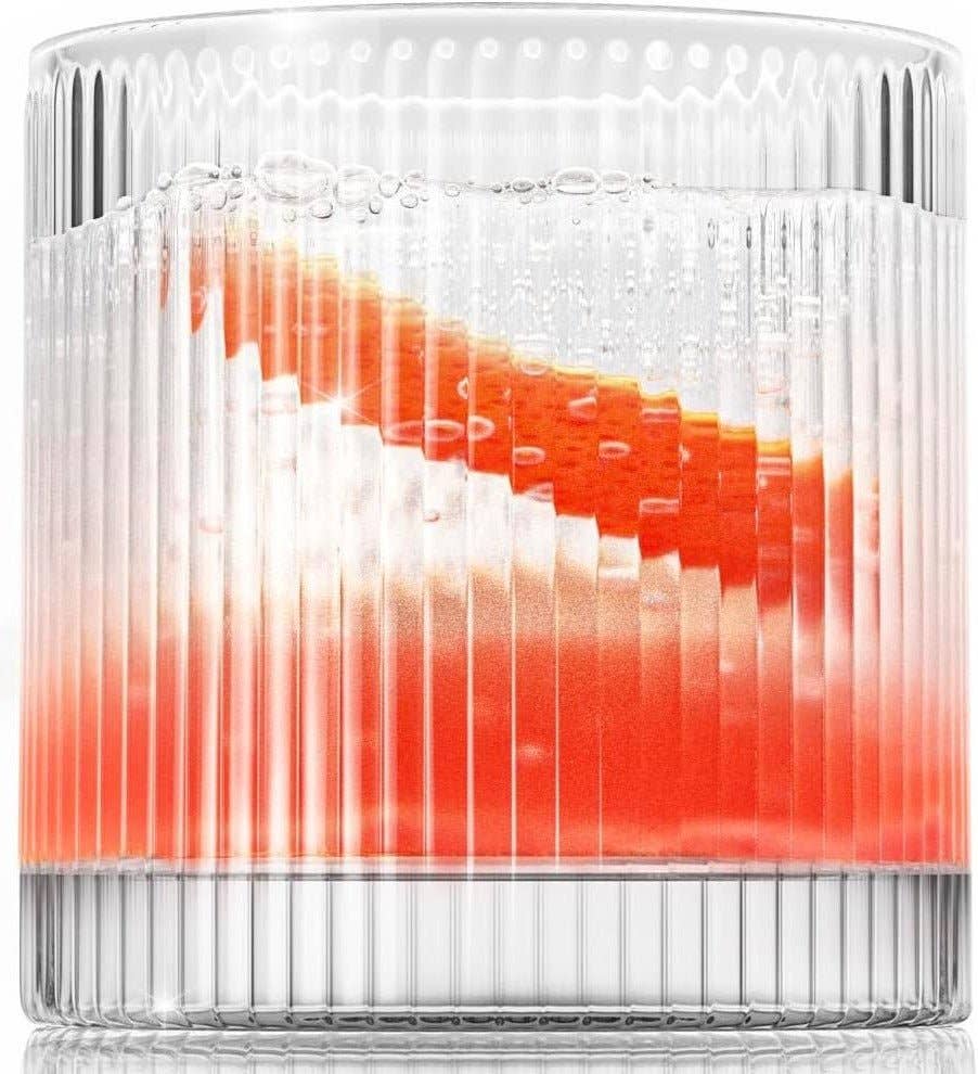 The Vintage Straight Line Tumbler – 10 oz (1pc) features clear, lead-free crystal with vertical ridges. A layered red and white drink with condensation appears striking in this chic, old-fashioned glass’s slanted design.