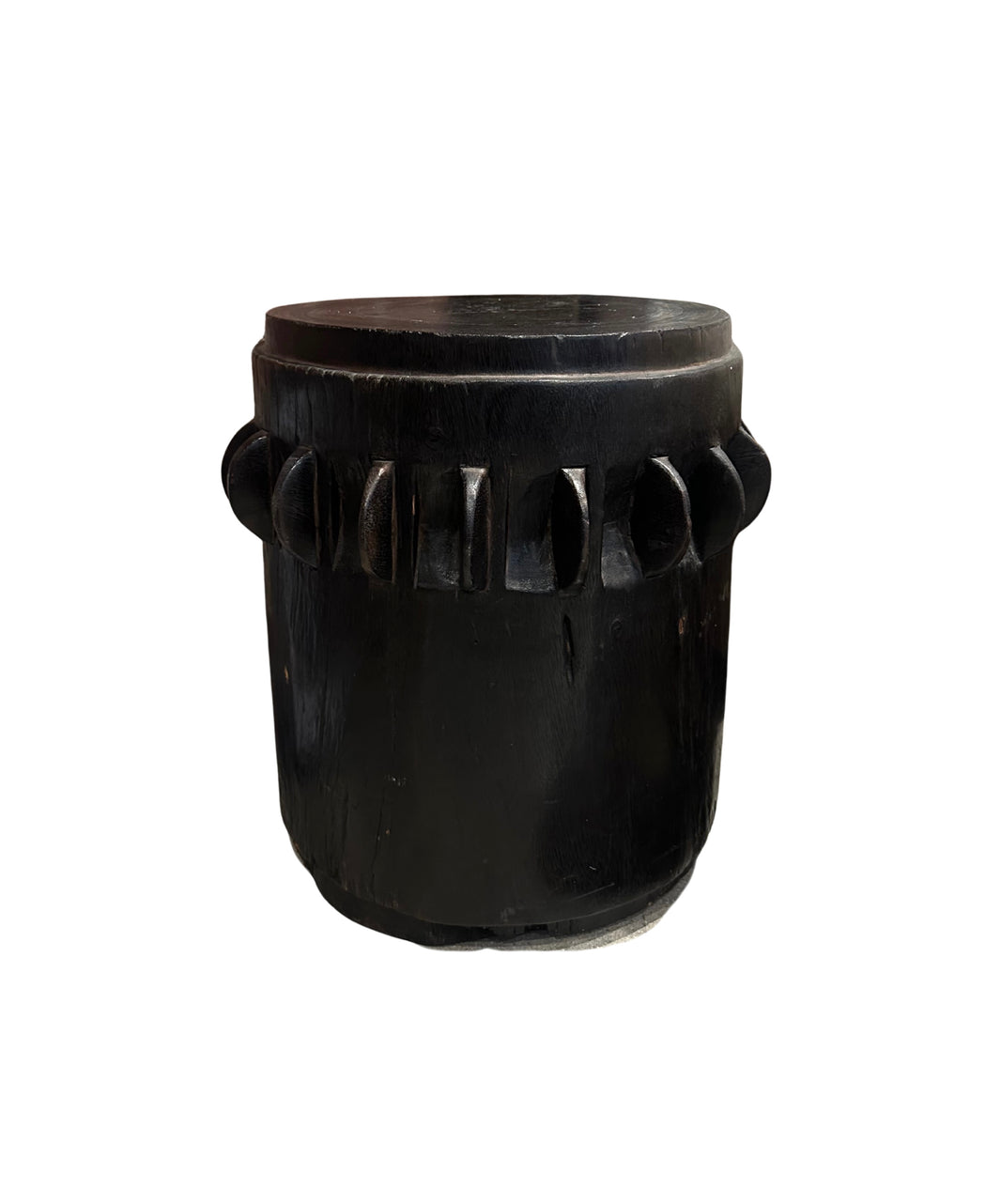 The Ebonized Wood Accent Table is a round, black wooden piece featuring a carved geometric pattern around its middle, displayed against a white background.