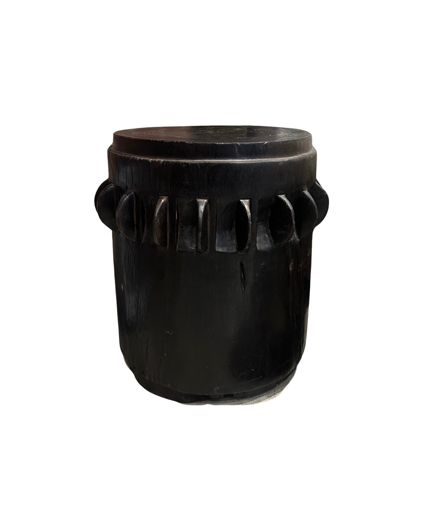 The Ebonized Wood Accent Table is a round, black wooden piece featuring a carved geometric pattern around its middle, displayed against a white background.