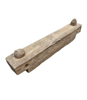 The Antique Wooden Dowry Chest is a long, rectangular chest with carved side patterns and two small pieces on its top ends, inspired by 19th-century Sulawesi design, displayed on a white background.